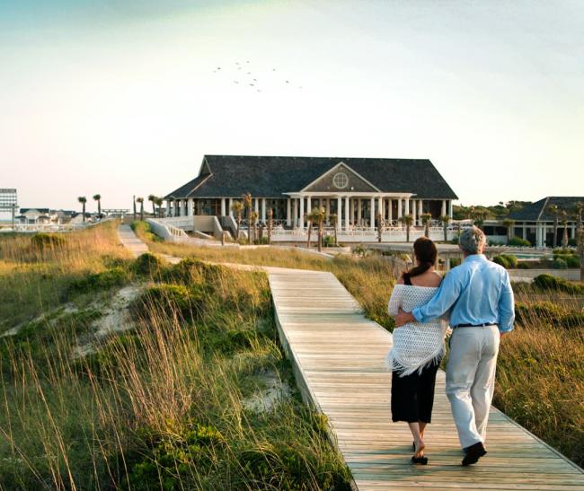Senior couple walking towards their luxury beachfront home. 