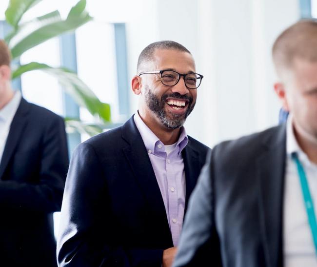 Insurance professional at gathering, smiling at other people.  